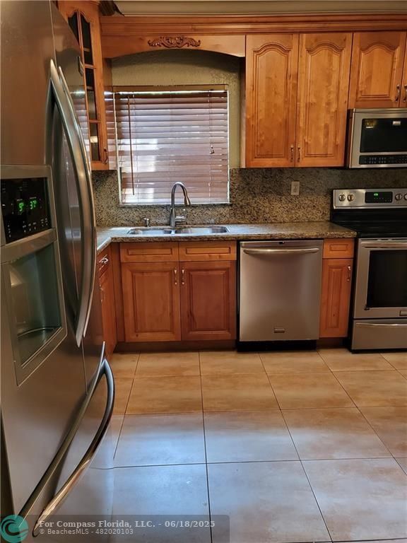 780 Northeast 199th Street, Unit E 101 Miami, FL 33179 - Photo 5 of 34 a kitchen with granite countertop a sink a stove top oven cabinetry and a sink
