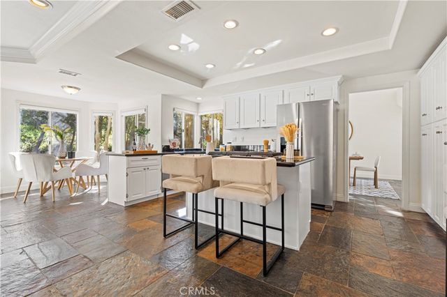 a kitchen with stainless steel appliances kitchen island granite countertop a refrigerator and cabinets