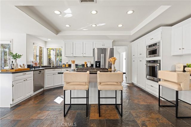 a kitchen with white cabinets and chairs