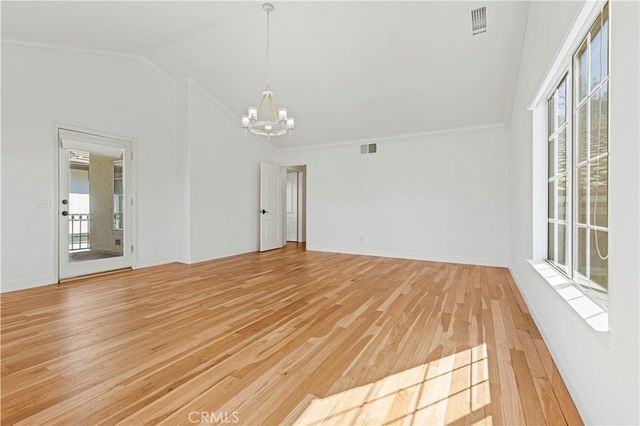 a view of an empty room with window and wooden floor