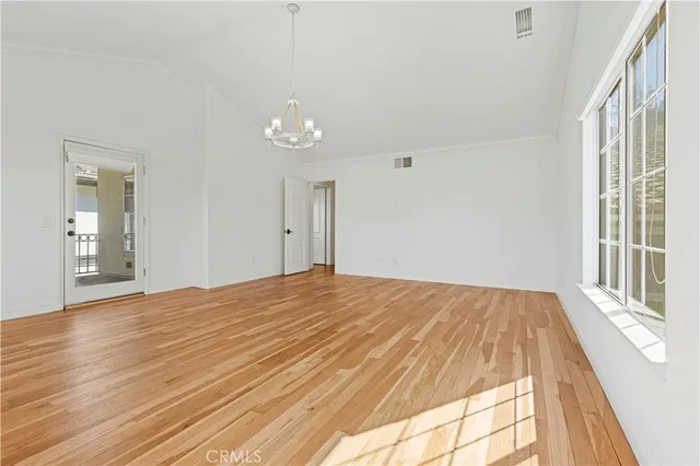 a view of an empty room with window and wooden floor