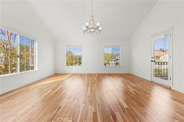 an empty room with wooden floor ceiling fan and window