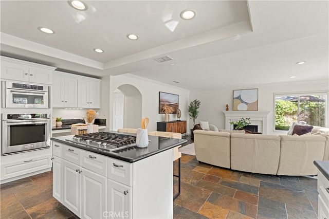 a kitchen with granite countertop a stove a sink dishwasher and white cabinets with wooden floor