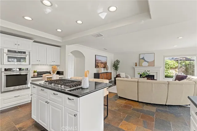 a kitchen with granite countertop a stove a sink dishwasher and white cabinets with wooden floor