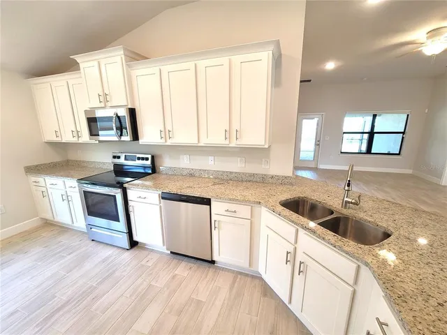 a kitchen with granite countertop a sink wooden cabinets and stainless steel appliances