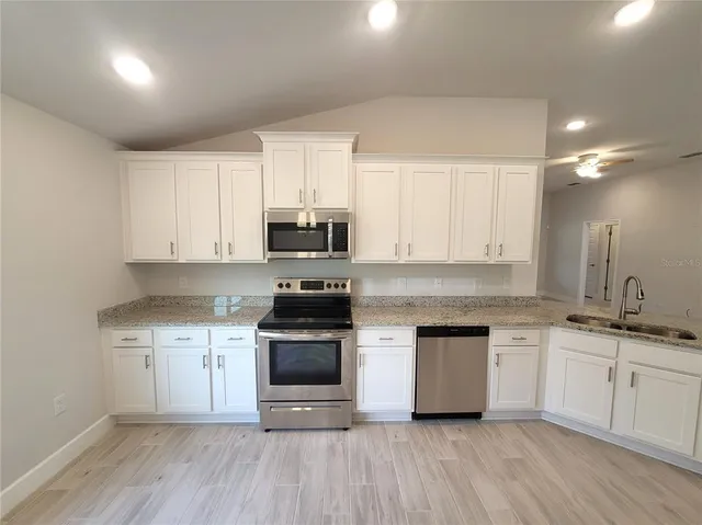 a kitchen with stainless steel appliances granite countertop a stove a sink and white cabinets