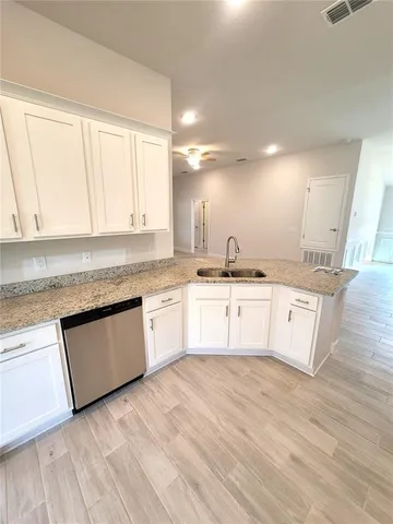 a large kitchen with granite countertop a white stove top oven and white cabinets