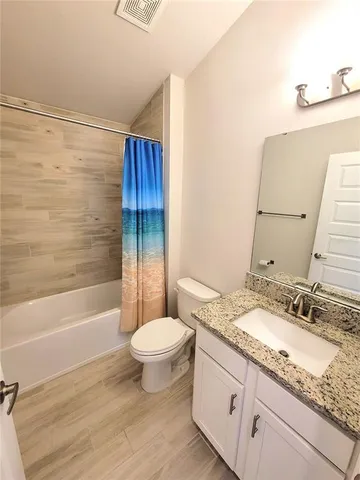 a bathroom with a granite countertop sink toilet a mirror and bathtub