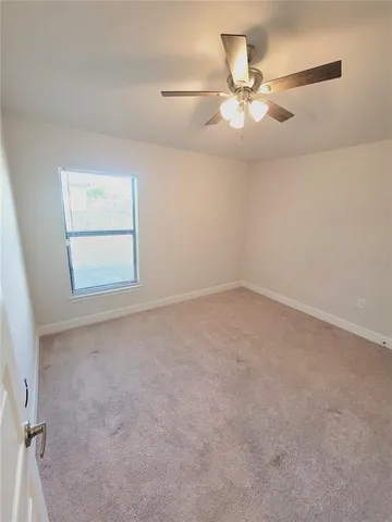 an empty room with windows and fan