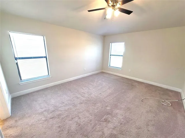 an empty room with windows and fan