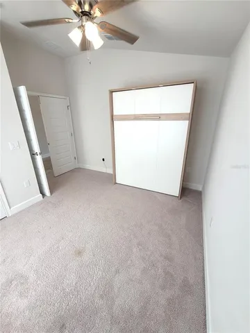 an empty room with a chandelier fan and windows