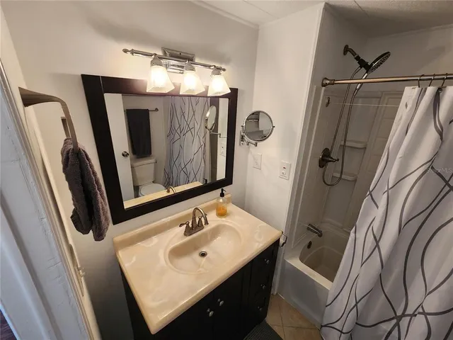 a bedroom with a bed a couch and a flat tv screen on the dresser