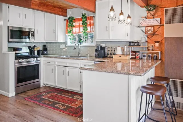 a kitchen with stainless steel appliances granite countertop a stove a sink and a microwave