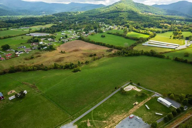 an aerial view of a houses with outdoor space and trees all around