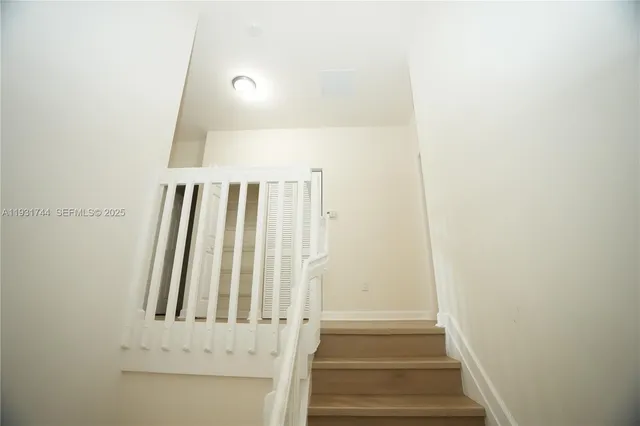 a view of staircase with white walls and white door