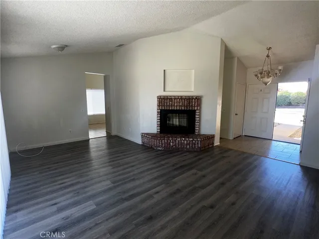 an empty room with wooden floor fireplace and staircase