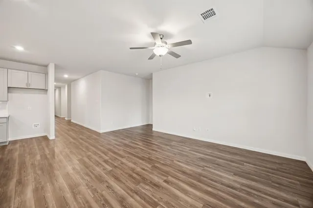 a view of empty room with wooden floor and fan