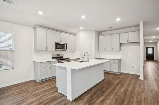 a kitchen with a sink stainless steel appliances and white cabinets
