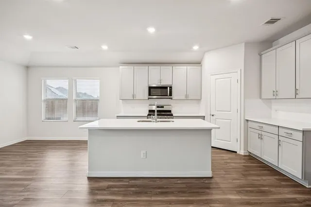 a kitchen with stainless steel appliances granite countertop a sink stove and wooden floor