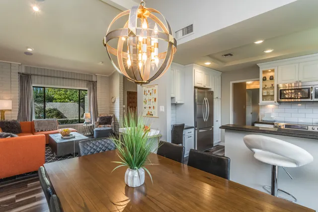 a kitchen with stainless steel appliances granite countertop a stove a refrigerator a sink a dining table and chairs with wooden floor