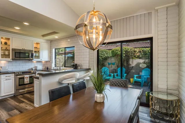 a kitchen with stainless steel appliances granite countertop a sink a stove white cabinets a dining table and chairs