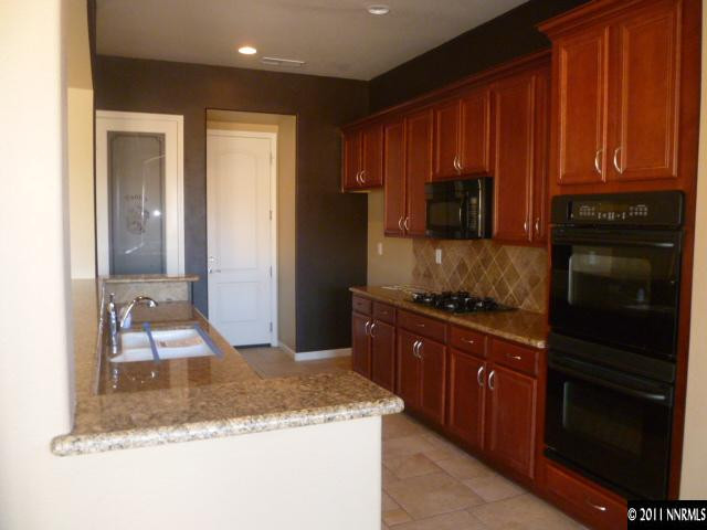 10122 Golden Spur Court Reno, NV 89521 - Photo 3 of 13 a kitchen with granite countertop wooden cabinets and stainless steel appliances