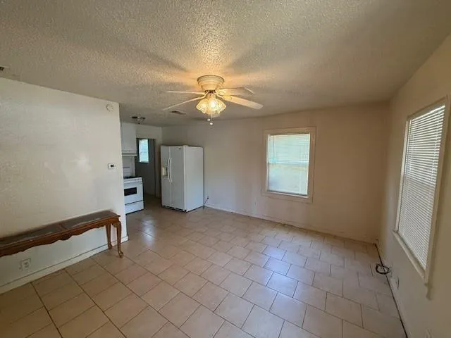 an empty room with windows and fan