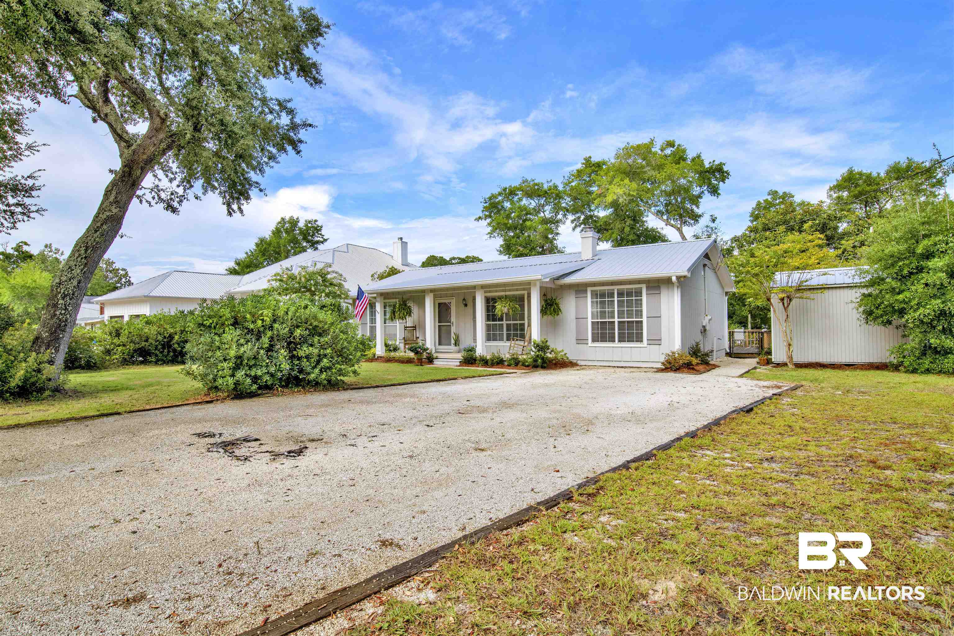 5415 Greentree Road Orange Beach, AL 36561 - Photo 4 of 55 Single story home with covered porch, a metal roof, a front lawn, and a chimney