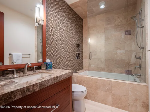 a bathroom with a granite countertop sink a toilet a mirror and bathtub