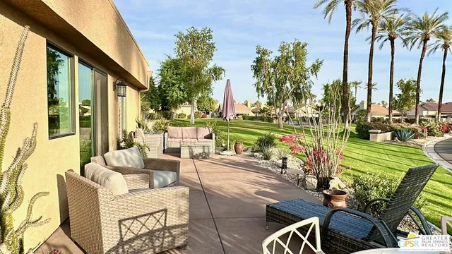 a view of a patio with couches table and chairs and palm trees