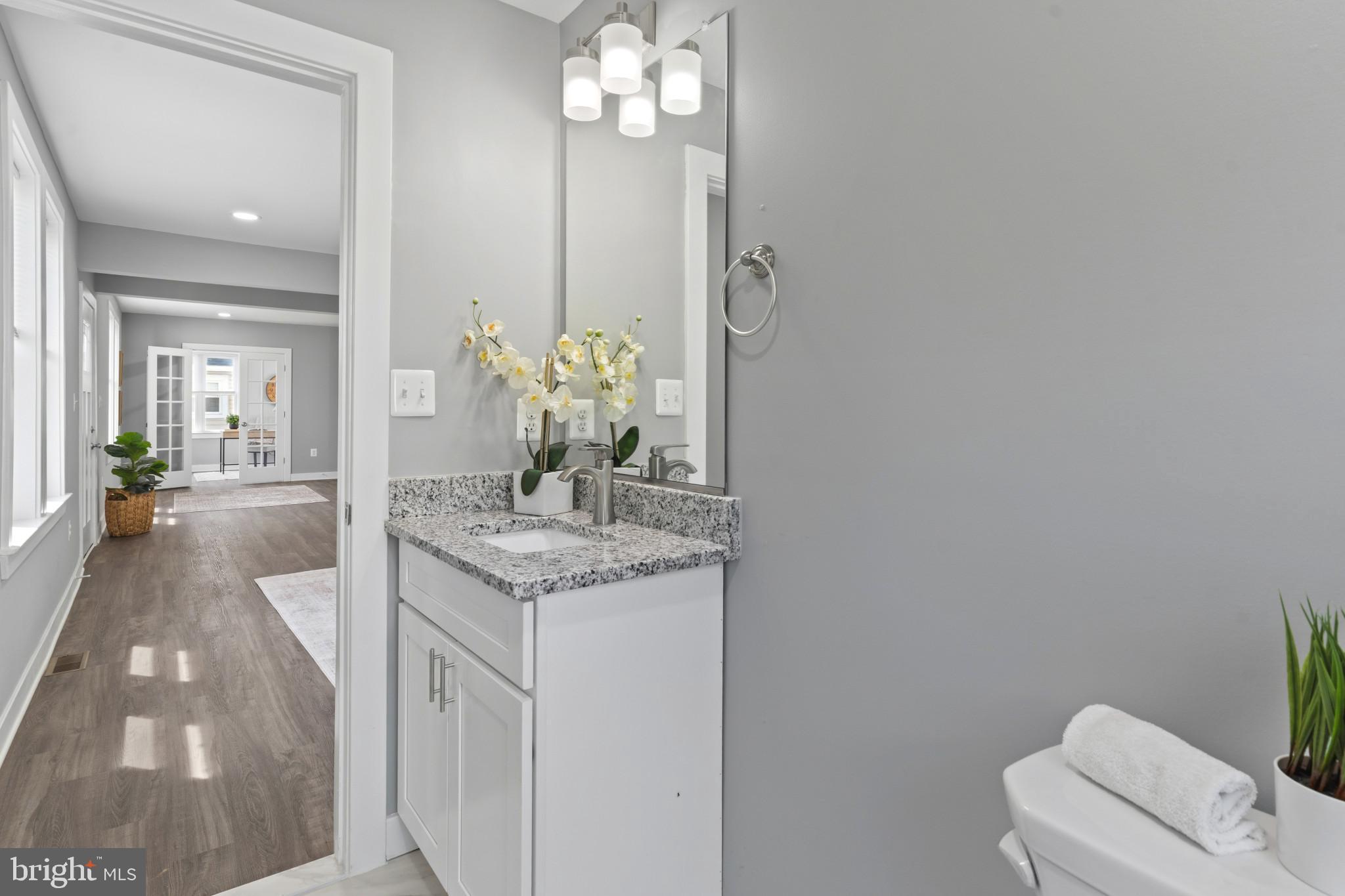 5728 Clover Road Baltimore, MD 21215 - Photo 14 of 40 a bathroom with a granite countertop sink a toilet and a mirror