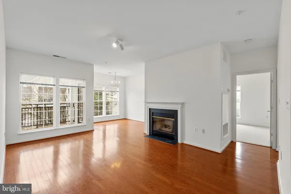 an empty room with wooden floor a fireplace and windows