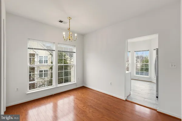 an empty room with wooden floor exposed radiator and windows