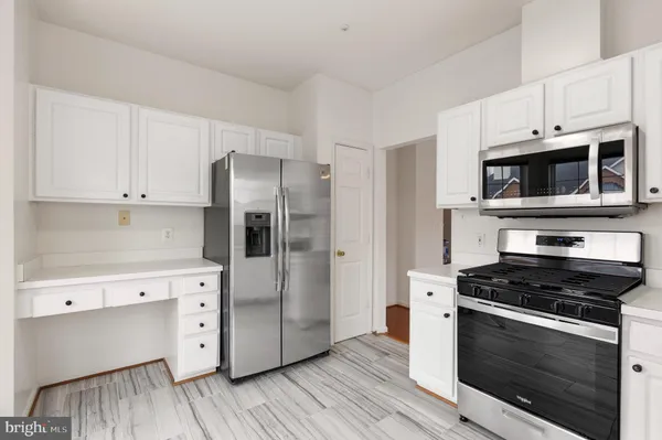 a kitchen with cabinets stainless steel appliances and wooden floor