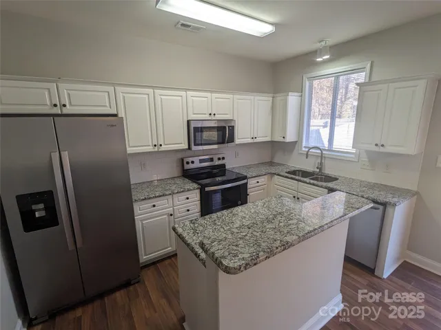 a kitchen with granite countertop a refrigerator stove a sink dishwasher and microwave