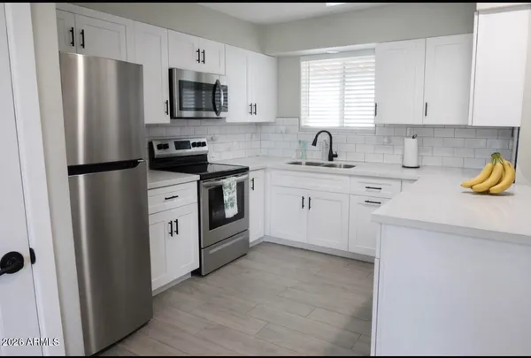 a kitchen with stainless steel appliances a stove a sink a refrigerator a window a counter space and cabinets