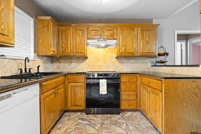 a kitchen with stainless steel appliances granite countertop a stove a sink and a microwave