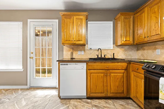 a kitchen with granite countertop wooden cabinets a stove a sink and a window
