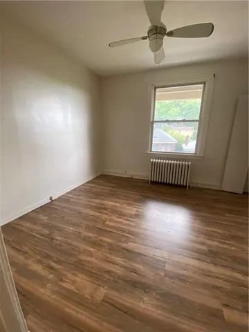 an empty room with wooden floor chandelier fan and windows