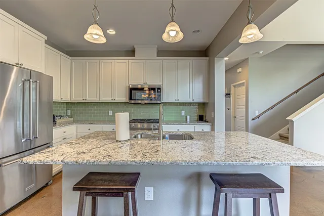 a kitchen with kitchen island granite countertop a sink a stove a microwave cabinets and stainless steel appliances