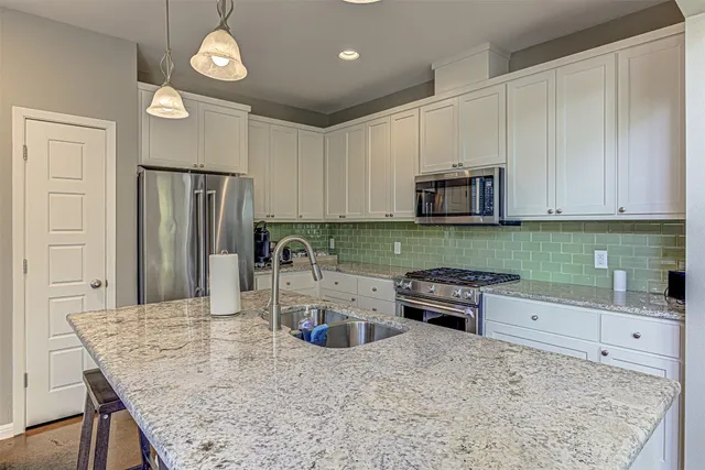 a kitchen with granite countertop a refrigerator and a stove top oven