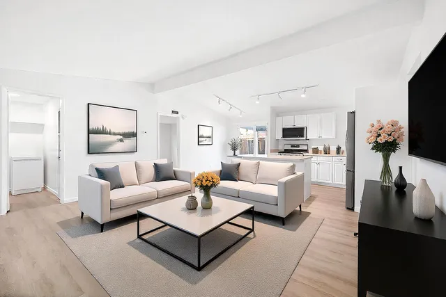 a living room with furniture a flat screen tv and kitchen view