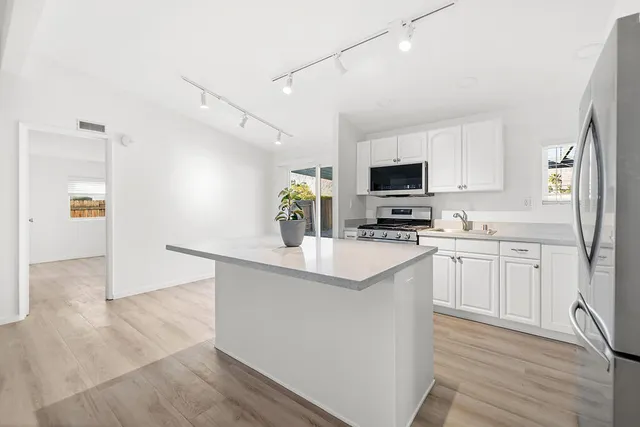 a kitchen with granite countertop a refrigerator stove top oven and sink
