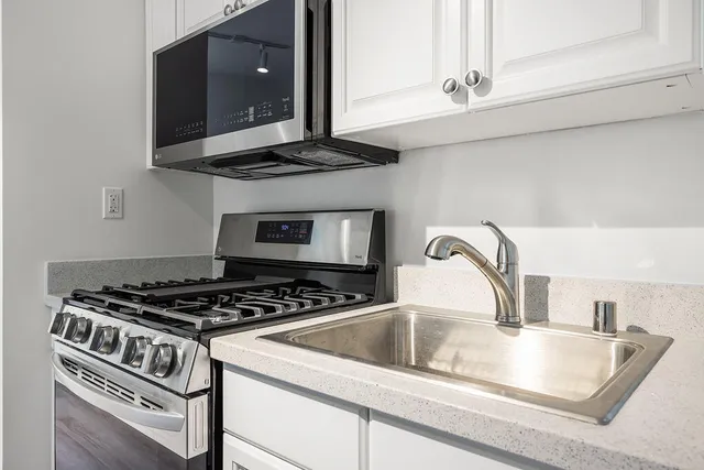 a kitchen with granite countertop a sink stove and cabinets