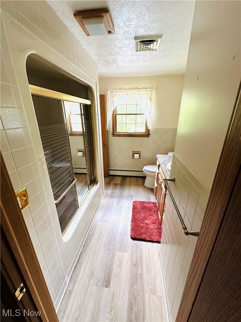 1684 Morris Street Mineral Ridge, OH 44440 - Photo 38 of 50 Bathroom featuring vanity, wood finished floors, a textured ceiling, and baseboard heating