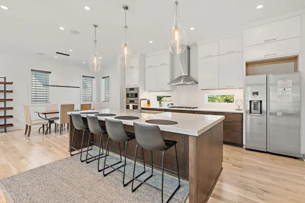 a kitchen with stainless steel appliances granite countertop a stove a sink a kitchen island and chairs