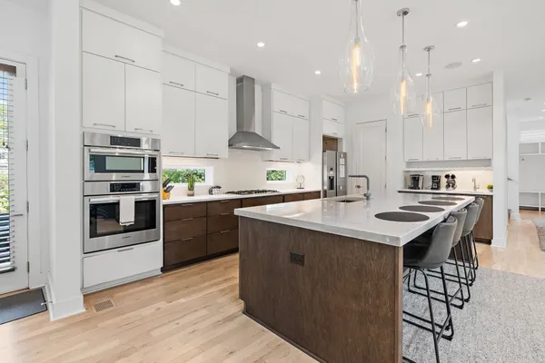 a kitchen with stainless steel appliances kitchen island a table chairs sink and cabinets