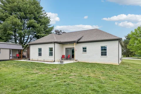 a front view of house with yard and trees in the background