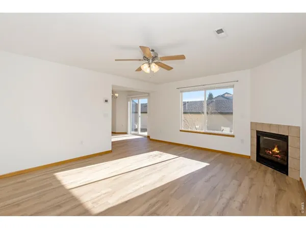 a view of an empty room with a fireplace and wooden floor