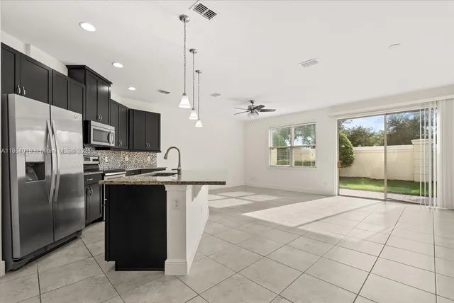 a kitchen with stainless steel appliances granite countertop a refrigerator a oven and a sink